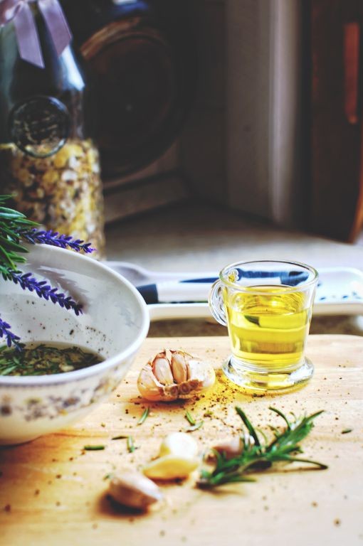 A rustic kitchen scene featuring a wooden cutting board with garlic cloves, rosemary, a small glass of oil, and a bowl of herbal mixture, representing natural antifungal treatments for Candida overgrowth.